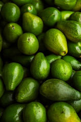 Fresh green avocados piled together, showcasing their natural texture and vibrant color. Perfect for concepts of healthy eating, organic food, and tropical fruit freshness.