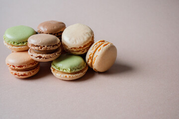 Multicolored macarons desserts with minimalistic beige background with copy space