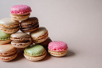 Pyramid made of multicolored macarons desserts on beige background