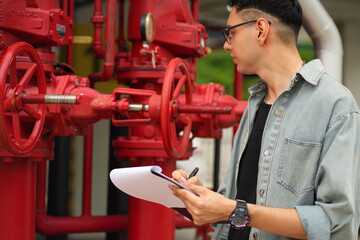 Male engineer inspects water pipelines in the engineering system area of the factory outside where...