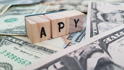 APY acronym made of wooden letter cubes on pile of US dollar banknotes. Annual Percentage Yield