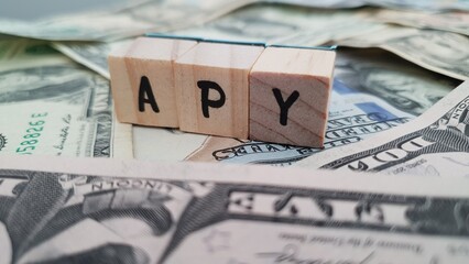 APY acronym made of wooden letter cubes on pile of US dollar banknotes. Annual Percentage Yield