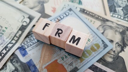 FRM acronym made of wooden letter cubes on pile of US dollar banknotes. Fixed Rate Mortgage