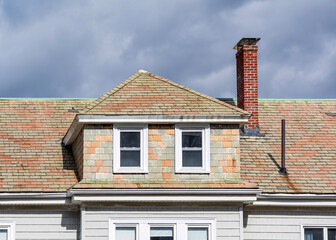 Aged slate roof and hipped dormer on an old residential building in Brighton, Massachusetts, USA
