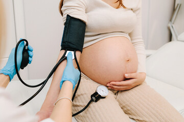 Gynecologist measures blood pressure for pregnant patient in the maternity center. High pressure problem during pregnancy.