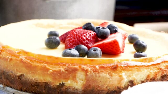 Baking a New York style cheesecake with strawberries, blueberries and a light lemon taste.   Baking a cheesecake in the kitchen with fresh berries.  Easy recipe for a classic cheesecake