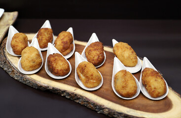 aperitivos de croquetas de jamón presentadas en una bandeja de madera de árbol 