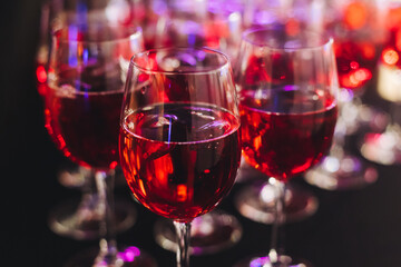 Alcohol setting on catering banquet table, row line of orange red coloured aperitif alcohol cocktails on party, negroni, spritz and others on bar counter, selection of liquor beverages on event