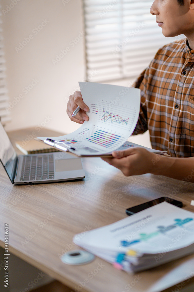 Poster businessman reviewing financial data, analyzing charts and graphs while working on a laptop in a mod