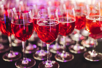 Alcohol setting on catering banquet table, row line of orange red coloured aperitif alcohol cocktails on party, negroni, spritz and others on bar counter, selection of liquor beverages on event