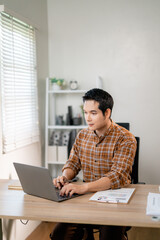 Professional working remotely, typing on laptop while sitting at home workspace desk