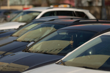 A long row of various cars are parked closely next to each other in a spacious parking lot, showcasing a variety of different models and colors