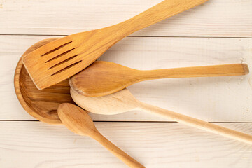 Wooden spoons and spatulas on a wooden table, close-up, top view.