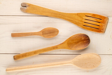 Wooden spoons and spatulas on a wooden table, close-up, top view.