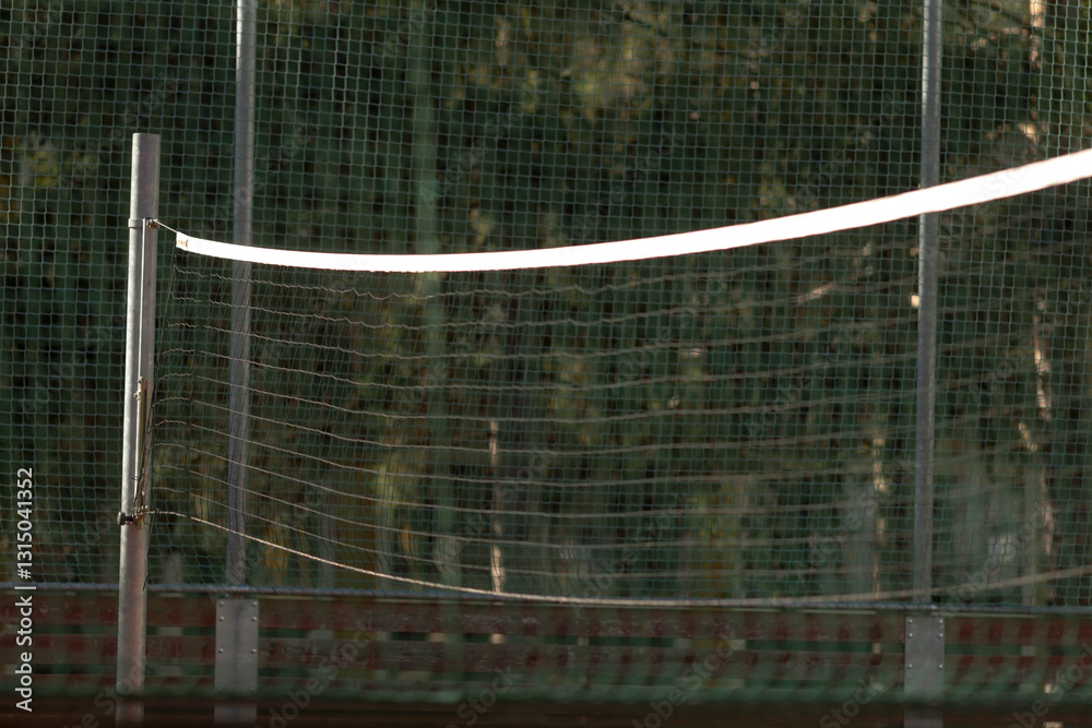Wall mural a volleyball net is enclosed by a sturdy fence, while trees beautifully line the background creating