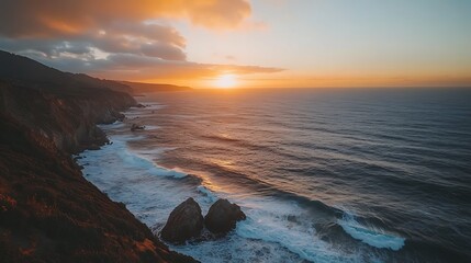 Obraz premium Vibrant sunset over dramatic coastline with ocean waves crashing against rocky cliffs.