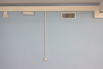 Minimalism and symmetry in the interior. Wiring, ventilation, lighting on the blue wall