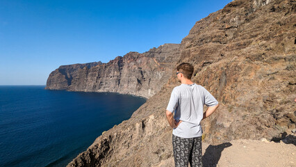 Tourist on background of giant cliffs Los Gigantes. Canary Islands. Spain. Atlantic Ocean.