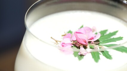 Closeup mixed passion fruit and sweet liquor cocktail decorated adding pink flower on top, making special creative drink menu list for advertisement in focusing alcohol refreshing showcase. Vinosity.