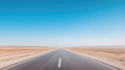 Naklejka premium long empty road stretches into horizon under vast clear blue sky