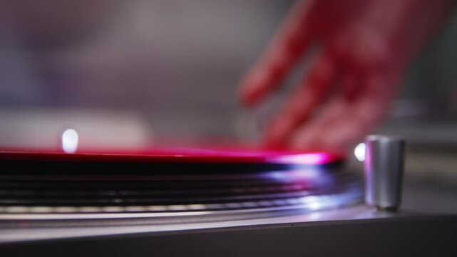 Close-up of a red vinyl record spinning on a turntable with the needle being carefully lowered onto it, ready to play music.