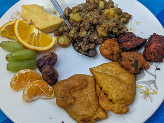 A plate of traditional Iftar. Featuring a savory mix of chickpeas, fried snacks, tofu, dates, grapes, and oranges, this meal offers a delightful blend of textures and flavors to break the fast.