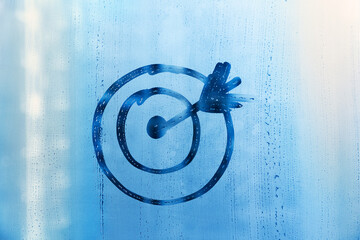 Doodle target and arrow on foggy glass on blue window