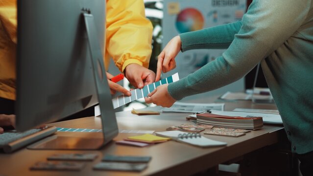 Diverse individuals engage in a collaborative color selection process in a modern office space, surrounded by tools and materials for creative design projects. SACTR