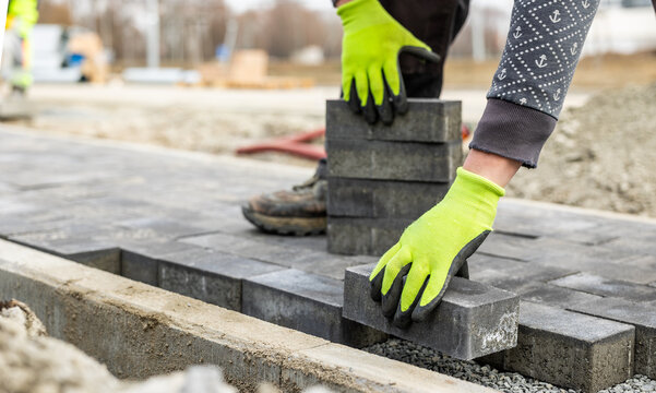 Construction worker placing paving stones for a new driveway