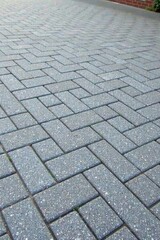 A Textured Pattern of Interlocking Gray Paving Stones Arranged in a Herringbone Design for a Durable and Attractive Outdoor Surface