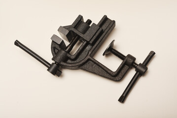 Small metal vise on a white background. The clamp. Tooling for locksmithing.