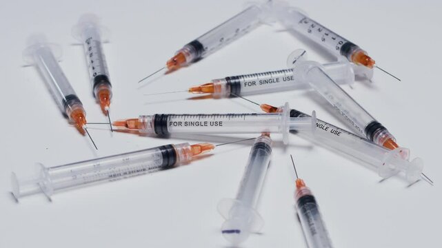 Amid a sterile setting, numerous single-use syringes with capped needles are arranged, highlighting their role in healthcare safety and medical procedures.