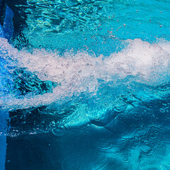 close-up abstract view of rolling and swirling water from slide waves with air bubbles. swimming pool water with aquamarine hues and light effect on a sunny day.