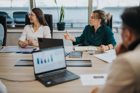 A diverse group of business people are gathered around a table, actively discussing ideas and strategies in a modern office setting. The atmosphere is collaborative and focused.