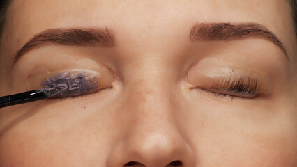 Woman face on modern eyelash lamination procedure in a professional beauty salon. Master applies...