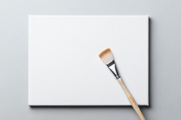 close-up of artist brush delicately poised above blank canvas with abundant copy space surrounding scene capturing