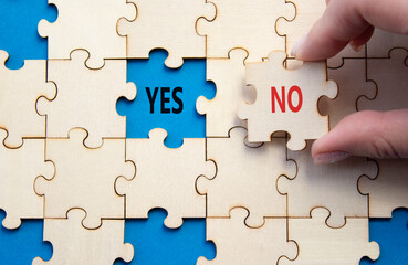 Fototapeta premium Yes or No symbol. Concept word Yes or No on wooden puzzle. Businessman hand. Beautiful blue background. Business and Yes or No concept. Copy space