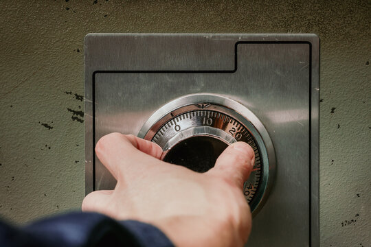 Person using security safe with mechanical combination lock or dial safe lock. Woman turning wheel combination lock with analog numbers. Close up of old fire proof steel safe. Selective focus.