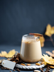 Hot almond coffee in a glass. Autumn foliage. Roasted coffee beans and almonds