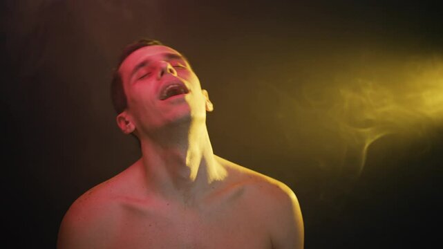Man sways euphorically in altered state under neon lights