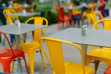 Colorful outdoor seating area with yellow and red chairs at a cafe in a park on a sunny day