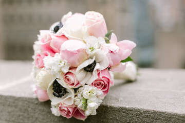 Beautifully arranged pink and white floral bouquet resting on a stone surface in an urban setting