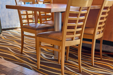 Warm restaurant interior featuring wooden chairs and tables, vibrant decor, and soft lighting, creating a welcoming atmosphere perfect for dining.