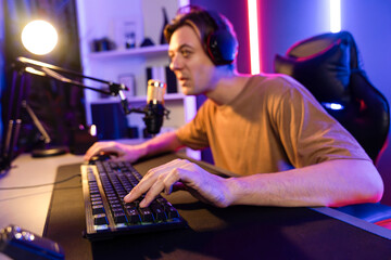 Host channel of gaming smart streamer playing online game to be winner, wearing headphone with viewers live steaming on media social online for selected team competition at neon light room. Pecuniary.