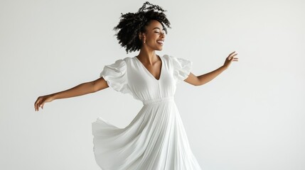 A woman in a white dress with a high-low hemline, striking a playful pose with arms wide on a white isolated background
