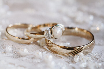 Elegant wedding rings and pearls beautifully arranged on lace fabric in soft natural light