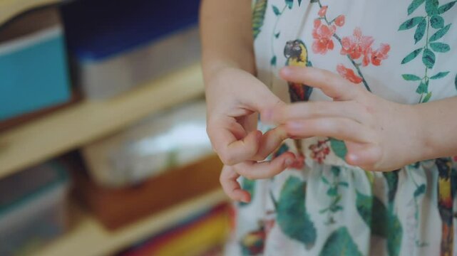 The girl is twisting her fingers, the nervous tic of the child, the girl is nervous