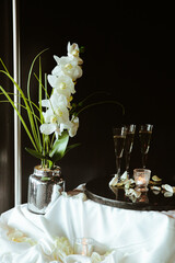 Elegant celebration setup with champagne glasses and white orchids on a table adorned with petals