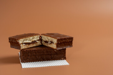 A delicious chocolate cake is cut in half and placed on white paper against a brown background. The cake is cut in half and placed on top of another cake, creating a visually appealing presentation.