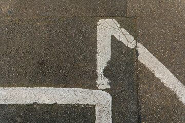 White paint marking on pavement forming an angular design in an urban environment during daylight